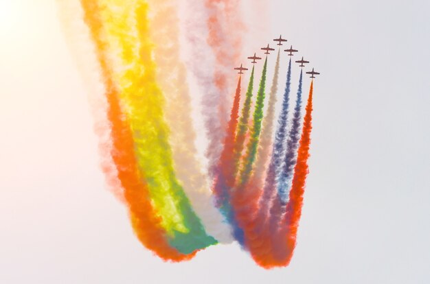Groupe d'avions à turbopropulseurs blancs avec une trace de fumée contre un ciel bleu.