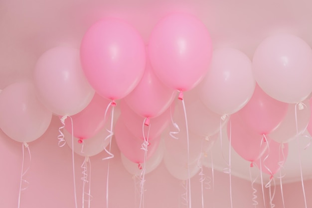 Groupe de ballons volants en gel rose et blanc sur un intérieur de maison de fond bleu