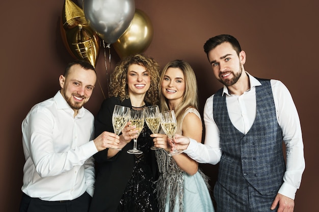 Groupe de beaux fêtards bien habillés célébrant des vacances ou un événement et buvant du vin mousseux