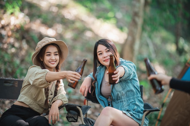 Groupe de belles femmes asiatiques amis voyageurs se détendant devant la tente de camping Ils aiment parler et boire de la bière avec plaisir et heureux ensemble