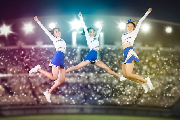 Groupe de belles pom-pom girls sautant dans le stade