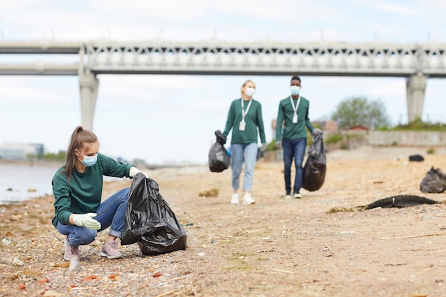 Groupe de bénévoles ramassant les ordures près de la rive de la rivière à l'extérieur