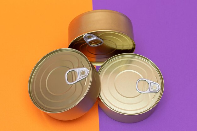 Un groupe de boîtes de conserve empilées avec des bords blancs sur un fond orange et violet partagé