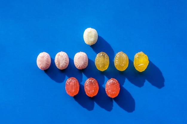 Groupe de bonbons colorés organisés en rangées sur fond bleu. Contraste les ombres dures. Concept de magasin de confiseries et de bonbons. Stock photo.