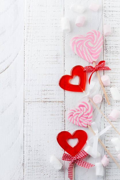 Groupe de bonbons divers festifs en forme de coeur sur fond de bois blanc