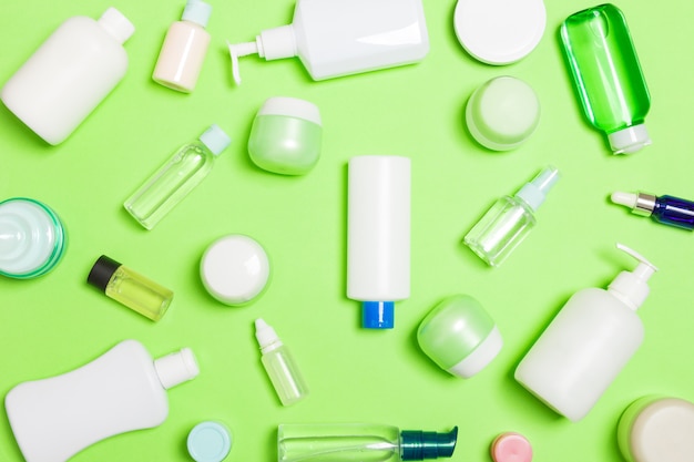 Groupe de bouteille de soin du corps en plastique Composition plate avec des produits cosmétiques sur fond vert espace vide pour votre conception. Ensemble de contenants cosmétiques blancs