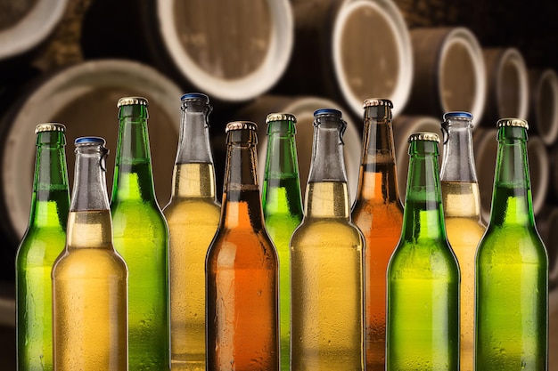 Photo groupe de bouteilles de bière froide et humide dans la cave avec fûts vintage