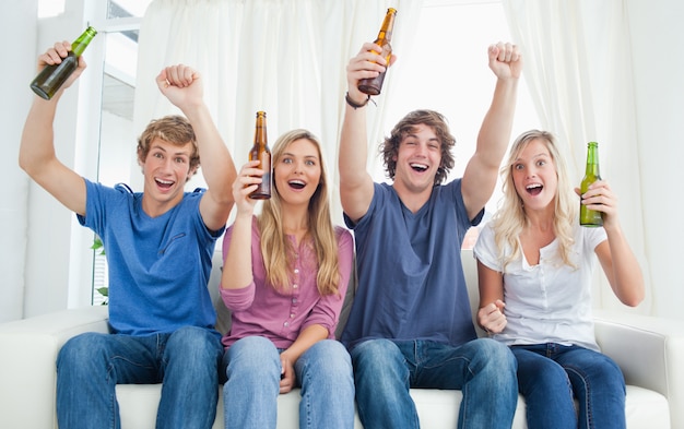Un groupe célébrant en regardant la caméra avec de la bière dans leurs mains