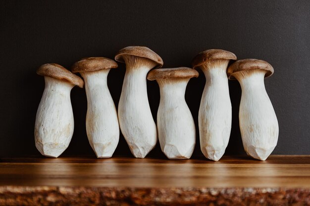 Photo groupe de champignons king oyster crus également connus sous le nom d'eryngii sur une planche de cuisine en bois