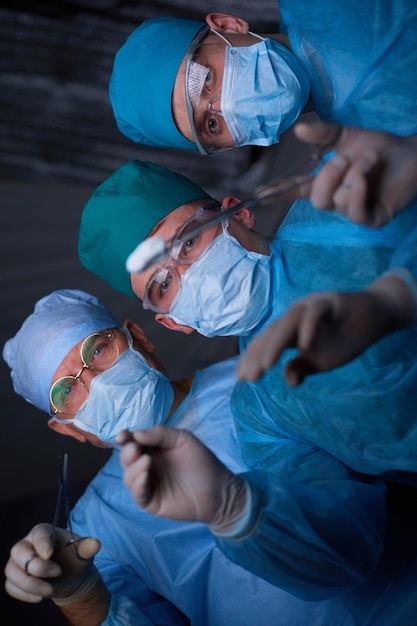 Groupe de chirurgiens au travail en salle d'opération tonique en bleu Équipe médicale effectuant une opération