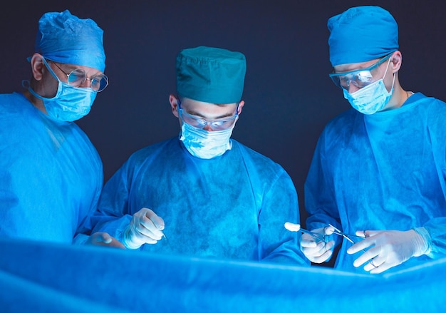 Groupe de chirurgiens au travail en salle d'opération tonique en bleu Équipe médicale effectuant une opération