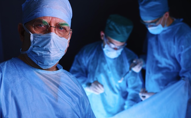 Groupe de chirurgiens au travail en salle d'opération tonique en bleu Équipe médicale effectuant une opération