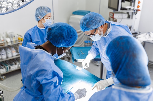 Groupe de chirurgiens en salle d'opération avec équipement chirurgical