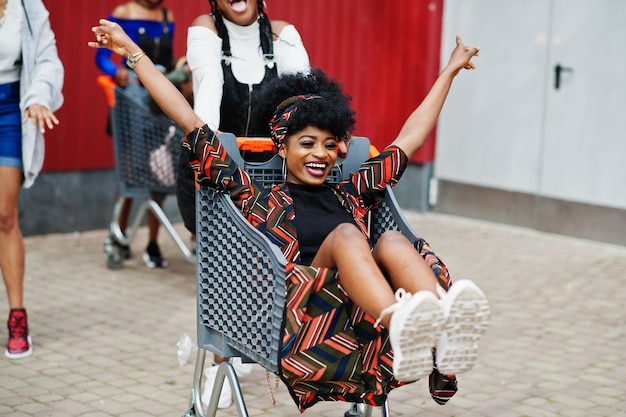 Groupe de cinq femmes afro-américaines avec des caddies s'amusant ensemble en plein air