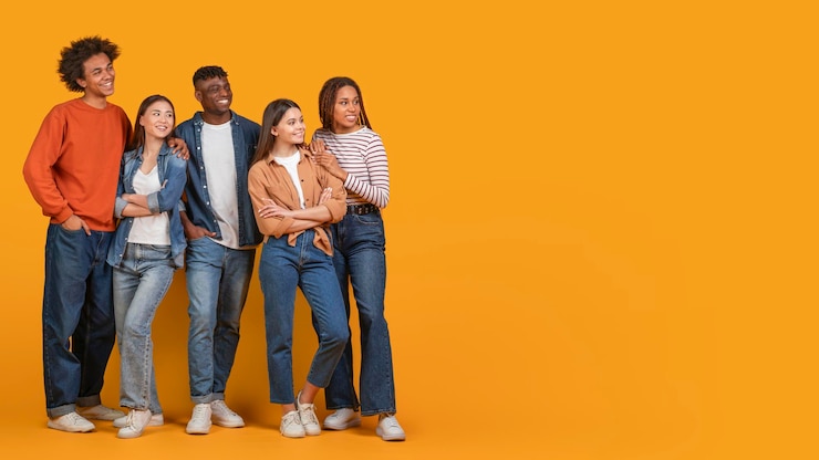 Photo un groupe de cinq jeunes adultes d'amis multiraciaux se tiennent ensemble devant un jaune vibrant