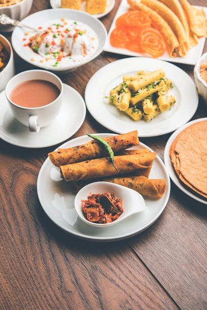 Groupe de collations gujarati comme jalebi-fafda, thepla, khaman dhokla, aloo bhujiya, khandvi, khakra, dahi vada, gathiya avec thé chaud