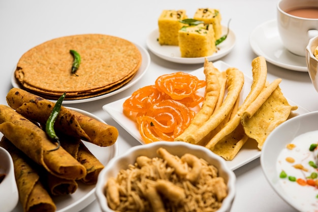 Groupe de collations gujarati comme jalebi-fafda, thepla, khaman dhokla, aloo bhujiya, khandvi, khakra, dahi vada, gathiya avec thé chaud