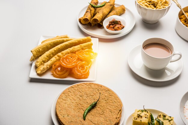 Groupe de collations gujarati comme jalebi-fafda, thepla, khaman dhokla, aloo bhujiya, khandvi, khakra, dahi vada, gathiya avec thé chaud