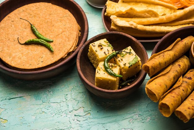 Groupe de collations gujarati comme jalebi-fafda, thepla, khaman dhokla, aloo bhujiya, khandvi, khakra, dahi vada, gathiya avec thé chaud