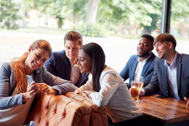 Groupe de collègues d'affaires posant pour selfies au bar après le travail