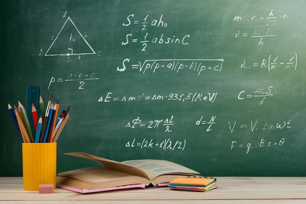 Groupe de concepts d'éducation et de lecture de livres colorés sur la table en bois dans le fond du tableau noir de la salle de classe