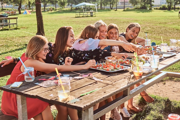 Groupe de copines assises à la table ensemble pour célébrer un anniversaire au parc extérieur.