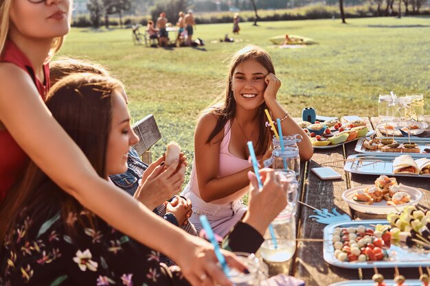 Groupe de copines assises à la table ensemble pour célébrer un anniversaire au parc extérieur.