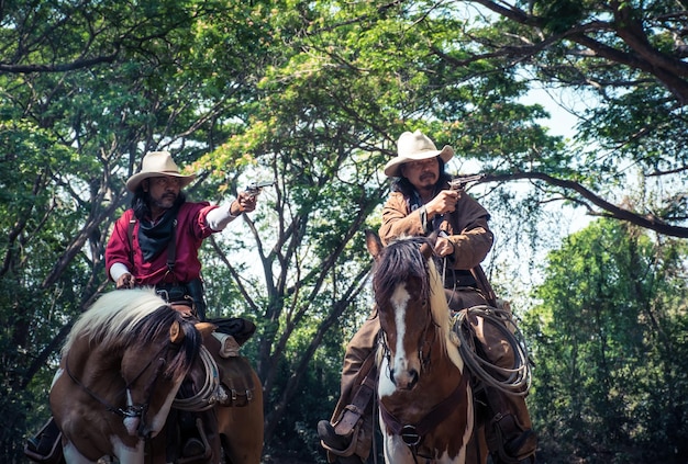 Un groupe de cow-boys à cheval et tenant un pistolet à la main est prêt à tirer