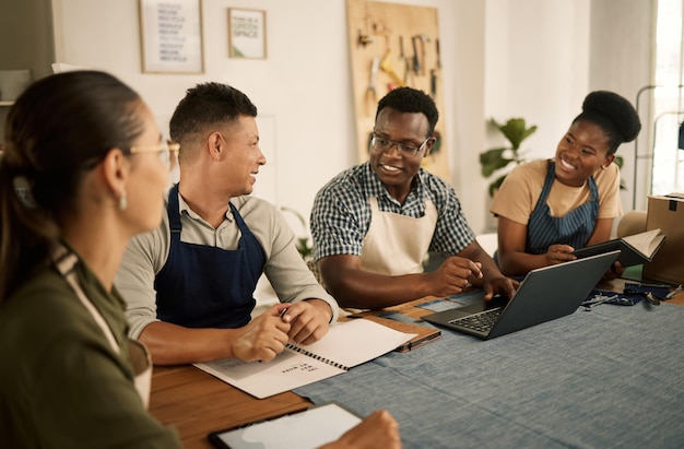 Un groupe de créateurs de vêtements et de créateurs de mode travaillant en équipe prenant des notes et faisant des recherches sur un ordinateur portable Un groupe de professionnels enthousiastes, positifs et branchés qui collaborent