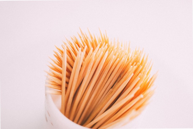 Photo groupe de cure-dents dans un récipient sur fond blanc le cure-dents est un morceau de petit bâton court en bois et pointu c'est un appareil pour enlever les particules de nourriture ou la saleté entre les dents