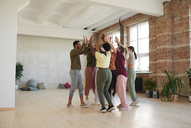 Photo groupe de danseurs se donnant un high five pendant la formation en studio de danse