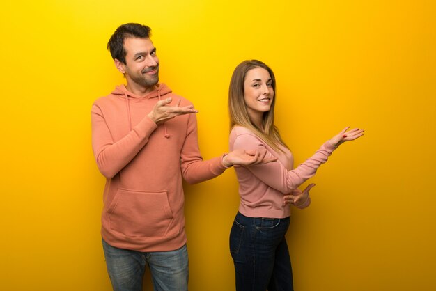 Groupe de deux personnes sur fond jaune, étendant les mains sur le côté
