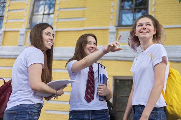 Groupe de discussion d'étudiantes, d'étudiantes adolescentes près d'un bâtiment en briques. Retour au collège, reprise des cours, études, lycée