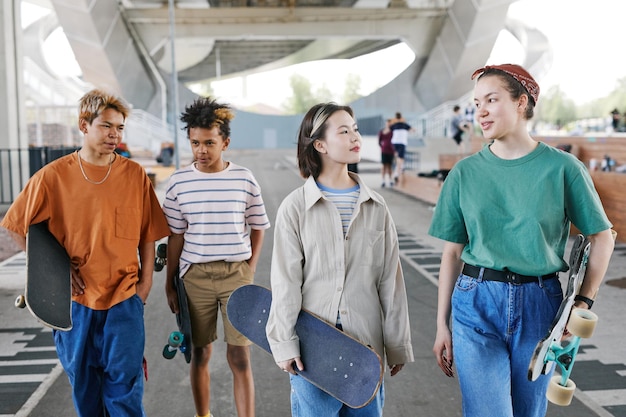 Groupe diversifié d'adolescents dans un skatepark à l'extérieur dans une zone urbaine portant des tenues sportives