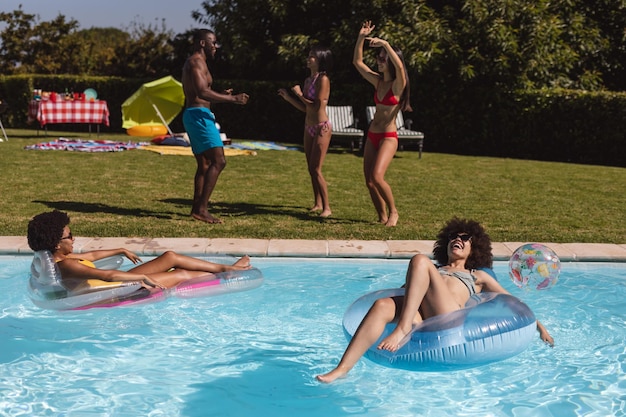 Groupe diversifié d'amis s'amusant et dansant lors d'une fête à la piscine. Sortir et se détendre à l'extérieur en été.