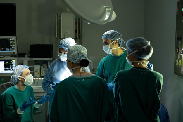 Groupe diversifié de chirurgiens hommes et femmes en discussion, en salle d'opération avant l'opération. Services hospitaliers, médicaux et de santé.