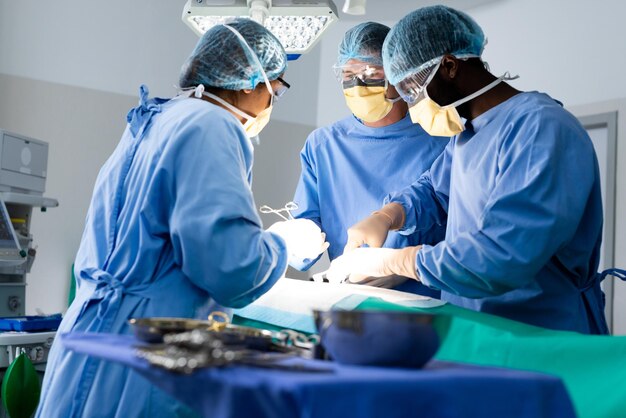 Groupe diversifié de chirurgiens opérant sur un patient en salle d'opération. Chirurgie, travail d'équipe, hôpital, services médicaux et de santé.