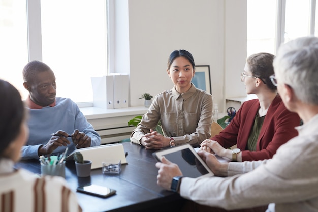 Groupe diversifié d'hommes d'affaires lors d'une réunion d'information au bureau, se concentrer sur une jeune femme d'affaires asiatique écoutant le patron