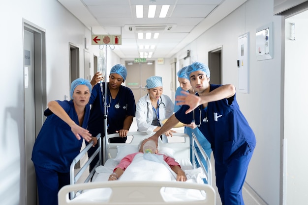 Groupe diversifié de travailleurs de la santé ouvrant la voie aux patients alités dans le couloir de l'hôpital. Services hospitaliers, médicaux et de santé.
