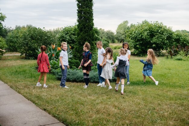 Un groupe d'écoliers court dans le parc en été. Bonheur, mode de vie. Enfance heureuse.