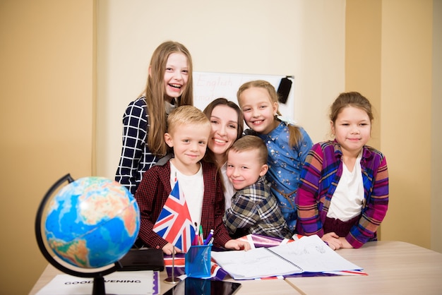 Groupe d'écoliers du primaire et d'enseignants travaillant à des bureaux dans la salle de classe.