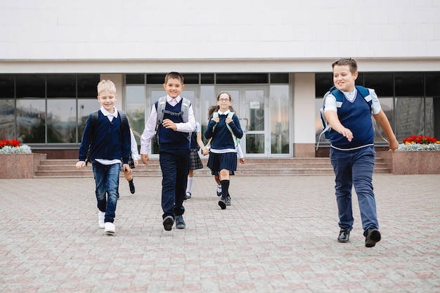 Groupe d'écoliers en uniforme sortant joyeusement et gaiement de l'école.