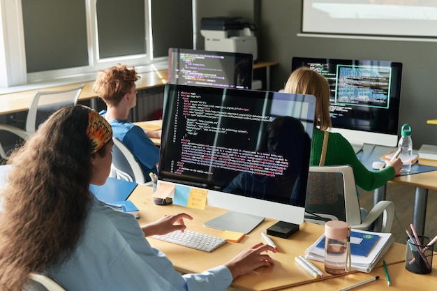 Groupe d'élèves écrivant des codes informatiques pendant la leçon à l'école