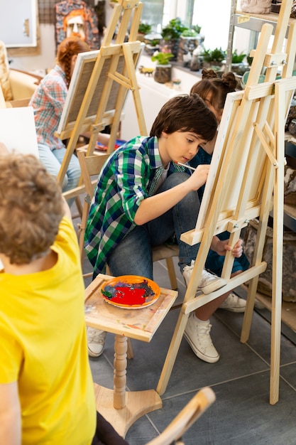 Groupe d'élèves talentueux coloriant leurs images à l'école d'art