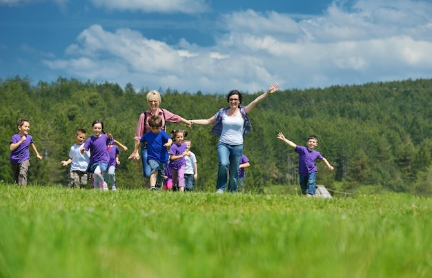 un groupe d'enfants d'âge préscolaire heureux s'amuse et joue à des cours en plein air dans la nature