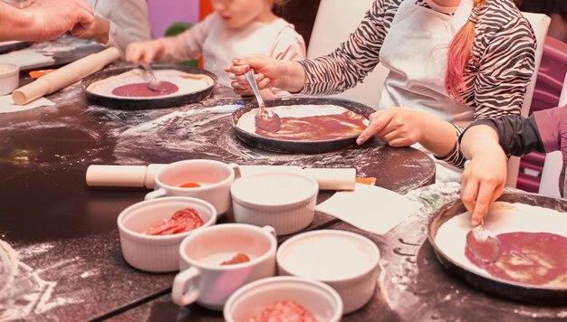 Un groupe d'enfants apprend à cuisiner des pizzas lors d'une master class