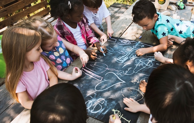 Groupe d&#39;enfants divers dessinant au tableau ensemble