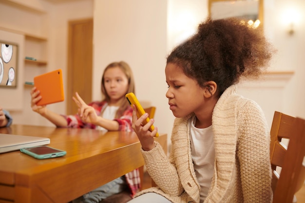 Un groupe d'enfants avec des gadgets en mains assis à la table