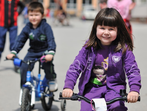 groupe d'enfants heureux apprenant à conduire un vélo en plein air lors d'une belle journée de printemps ensoleillée