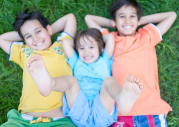 Groupe d&#39;enfants heureux en été allongé sur l&#39;herbe verte